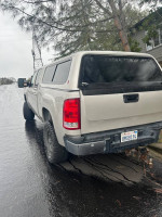 2007 GMC Sierra 2500HD 4x4 truck with camper shell parked on a wet road