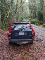 Rear view of a 2004 Volvo XC90 T6 parked on a wooded road, showing unique design and condition.