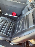 Interior view of a 1970 Ford Mustang with black leather seats and storage compartment.