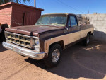1977 GMC C-35 Sierra classic pickup truck in storage, showing faded paint and minor damage.