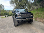2006 Chevrolet Silverado 1500 with 121,000 miles, lifted, and equipped with new mud terrain tires, parked on a scenic road.