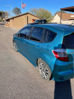 2013 Honda Fit Sport in turquoise color parked, showcasing its compact design and spacious rear seating.