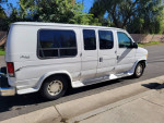 2000 Ford E-150 Triton camper conversion van parked on the street, showcasing its clean exterior and spacious design.